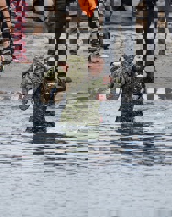A Law Enforcement Torch Run Polar Plunge participant carries another participant on their shoulder as they enter the water.