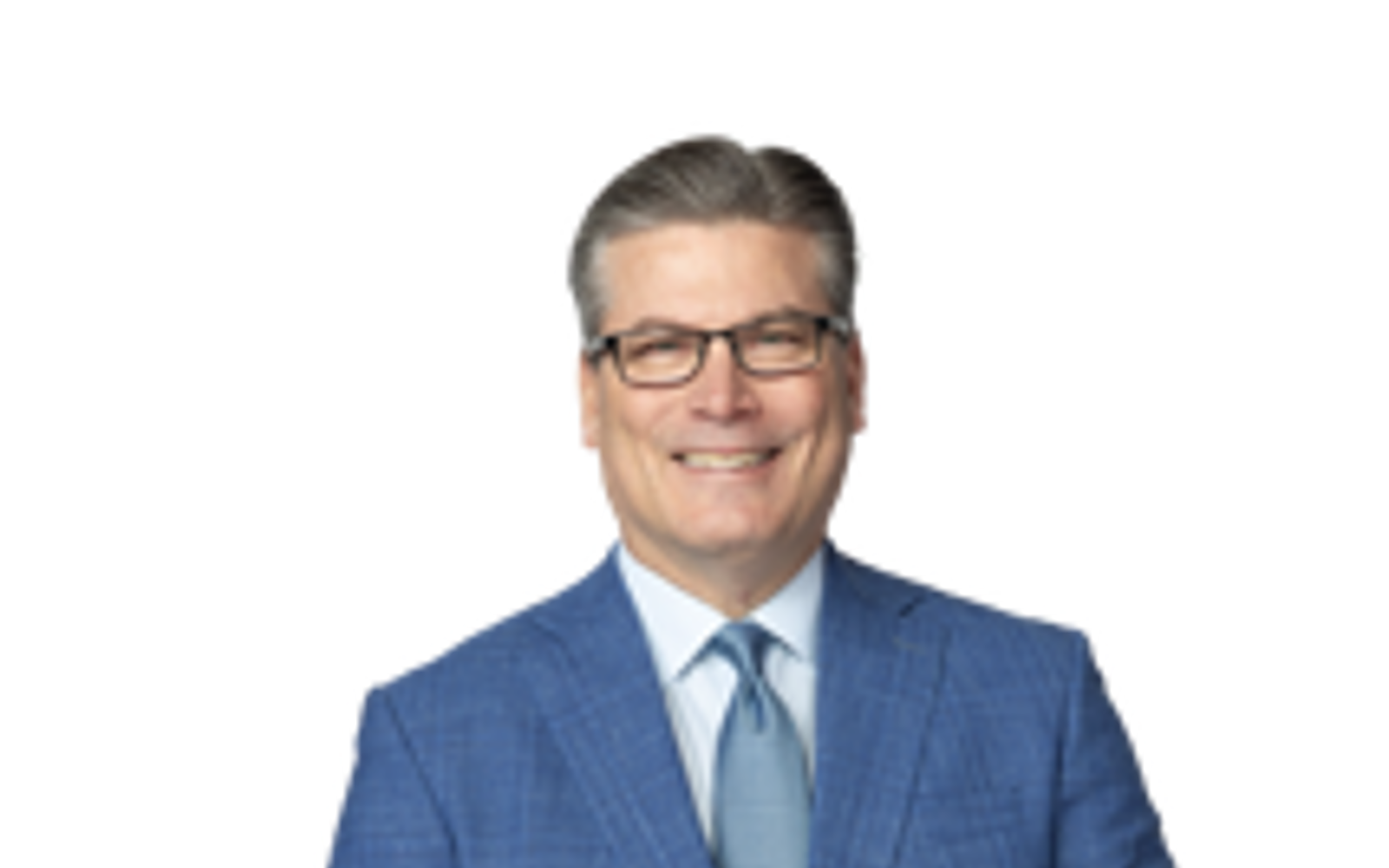 Un homme en costume bleu sourit à la caméra.