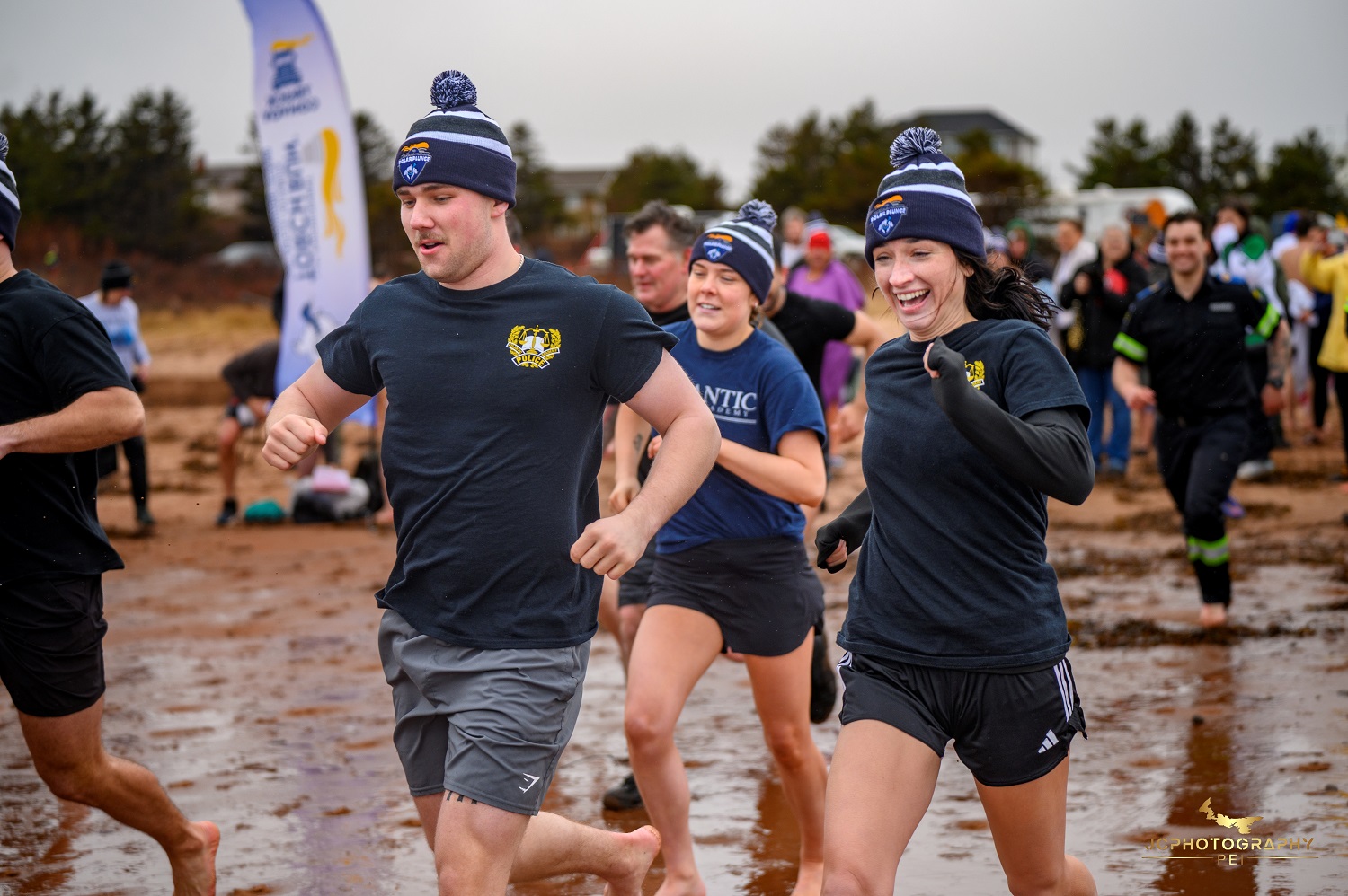 A group of people run into the water on the beach for a Polar Plunge event