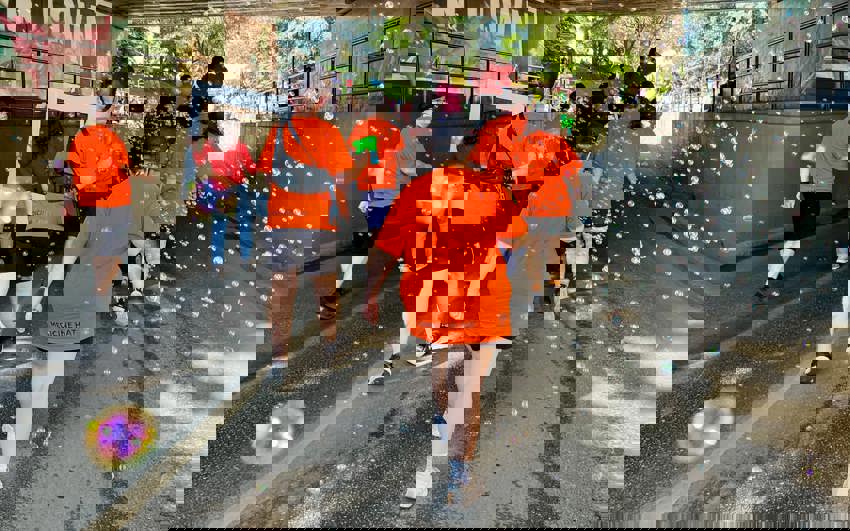 Special Olympics athletes in orange "Medicine Hat" t-shirts, are walking in a parade. The photo was taken from behind the action, and in the photo lots of bubbles are present all around the athletes.