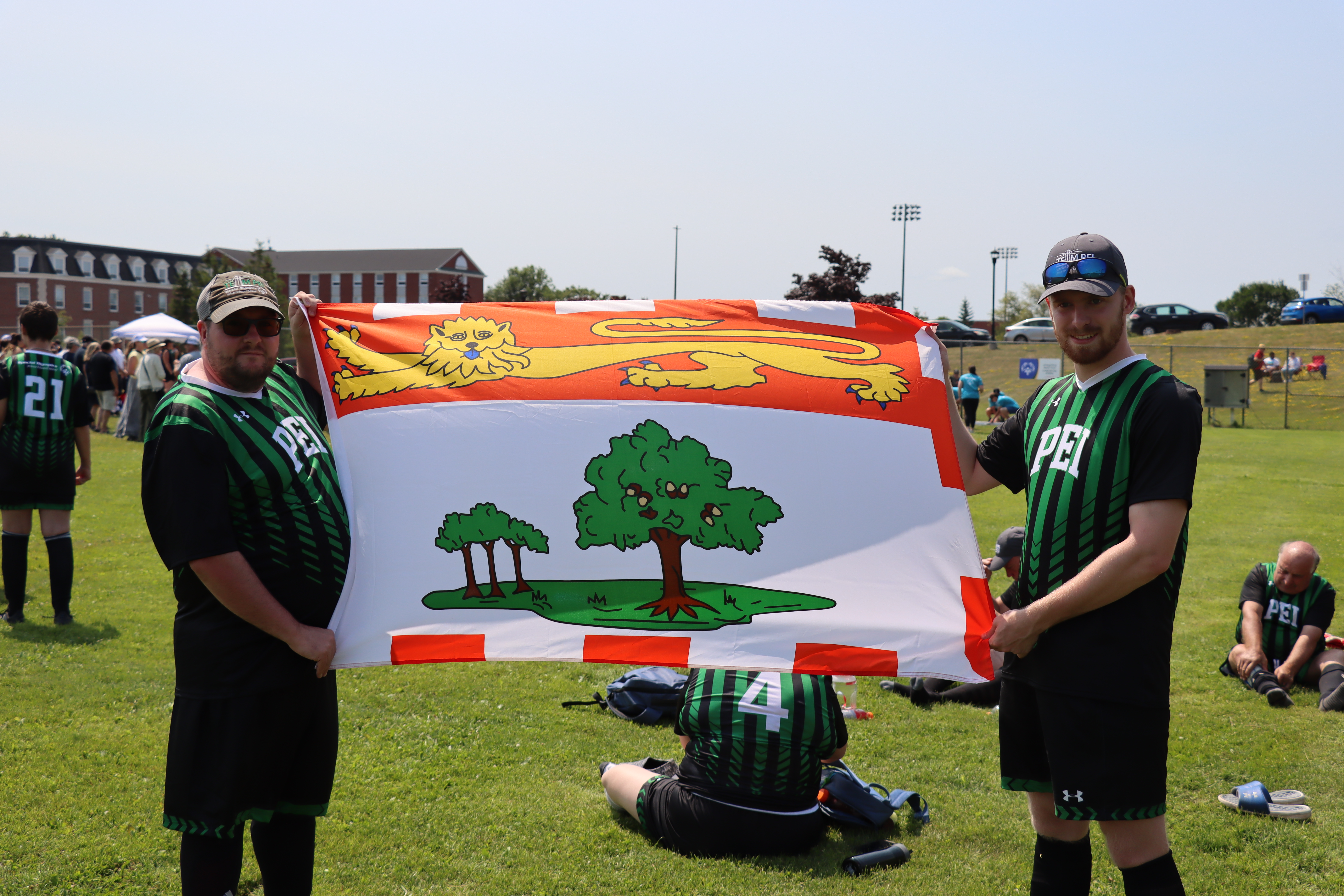 2 Team PEI athletes standing with the PEI flag