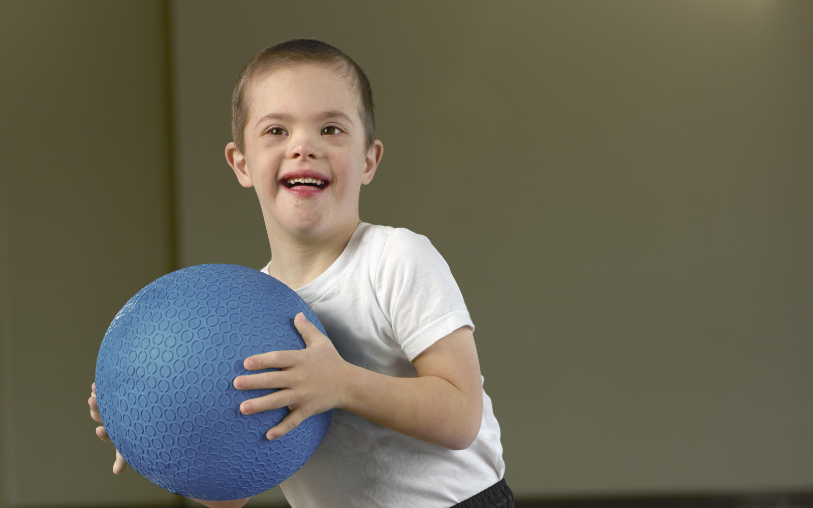 Toddler boy in a white shirt and black shorts holding a blue ball 