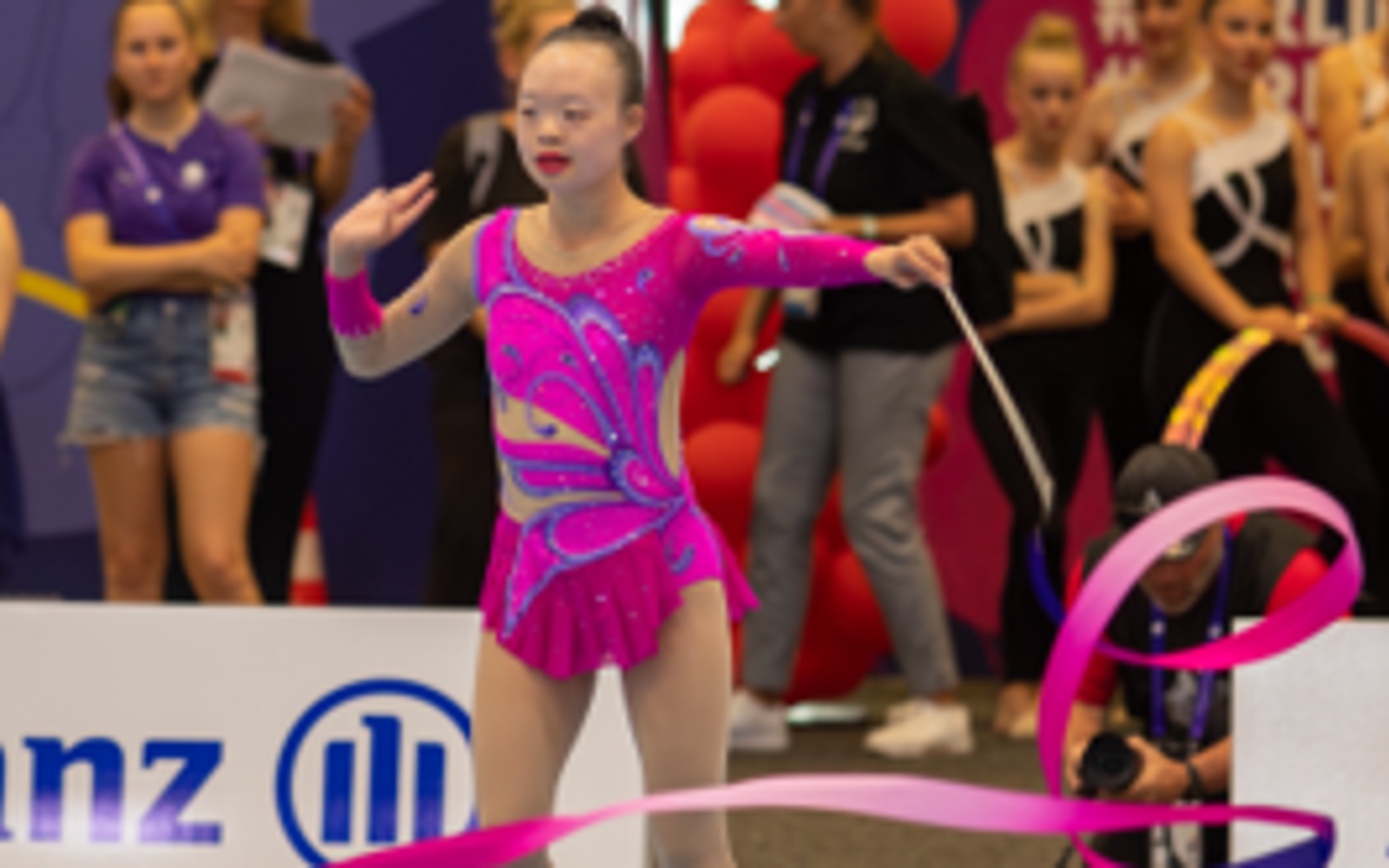 Girl in a purple bodysuit with a rhythmic gymnastics baton.