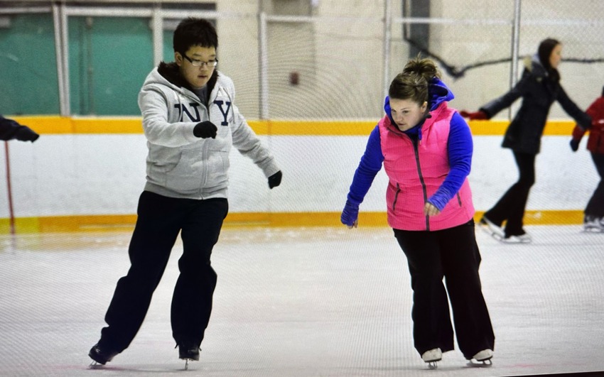 two people on an ice rink, practicing skating. 