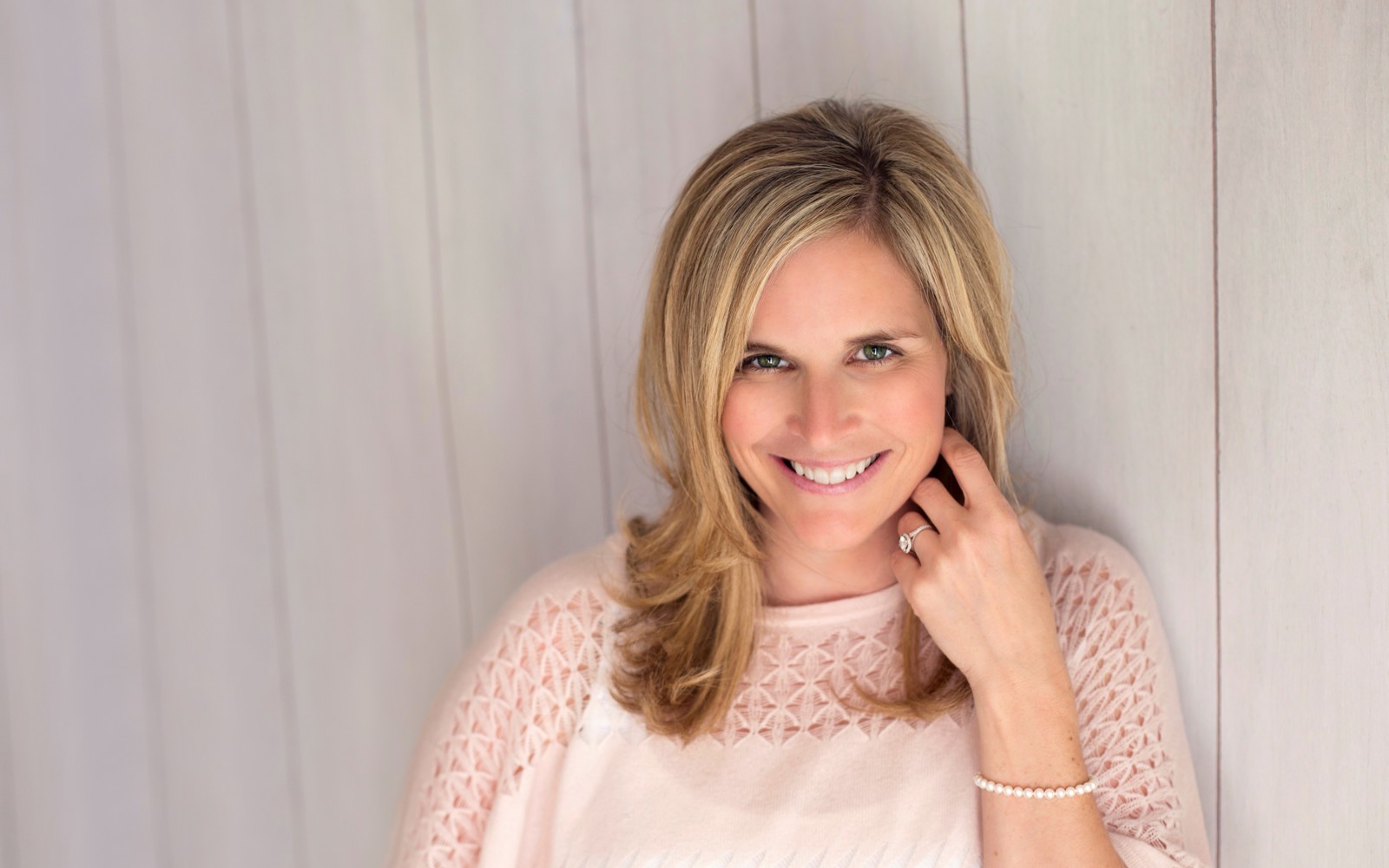 Portrait d'une femme aux longs cheveux blonds portant un pull blanc.