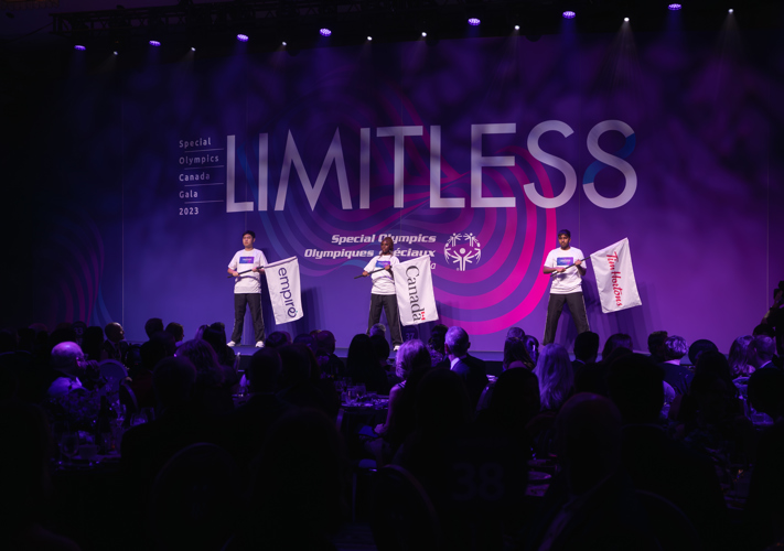 Three people on stage holding flags. 