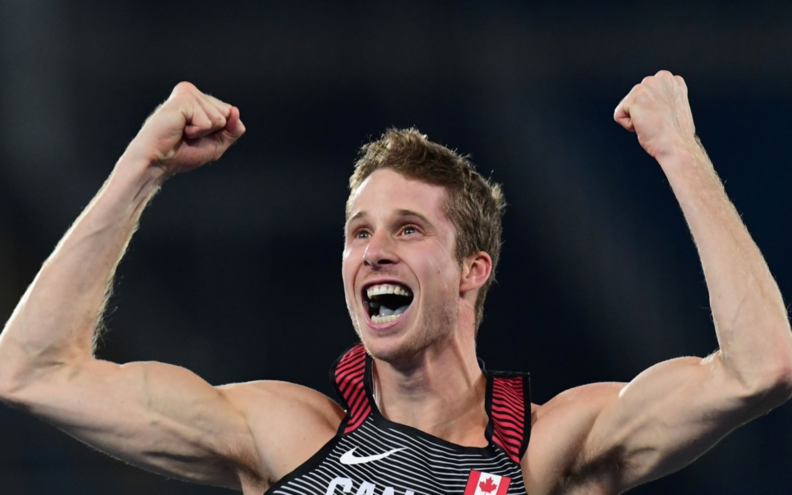 Homme en débardeur athlétique, les bras levés en signe d'encouragement.