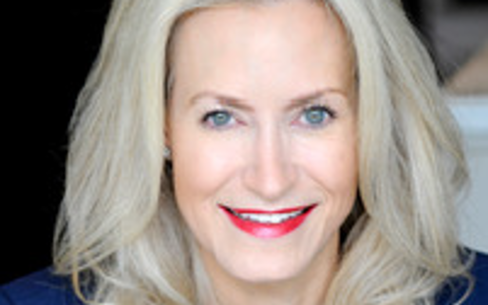 Femme aux longs cheveux blonds portant une robe bleue et des perles.