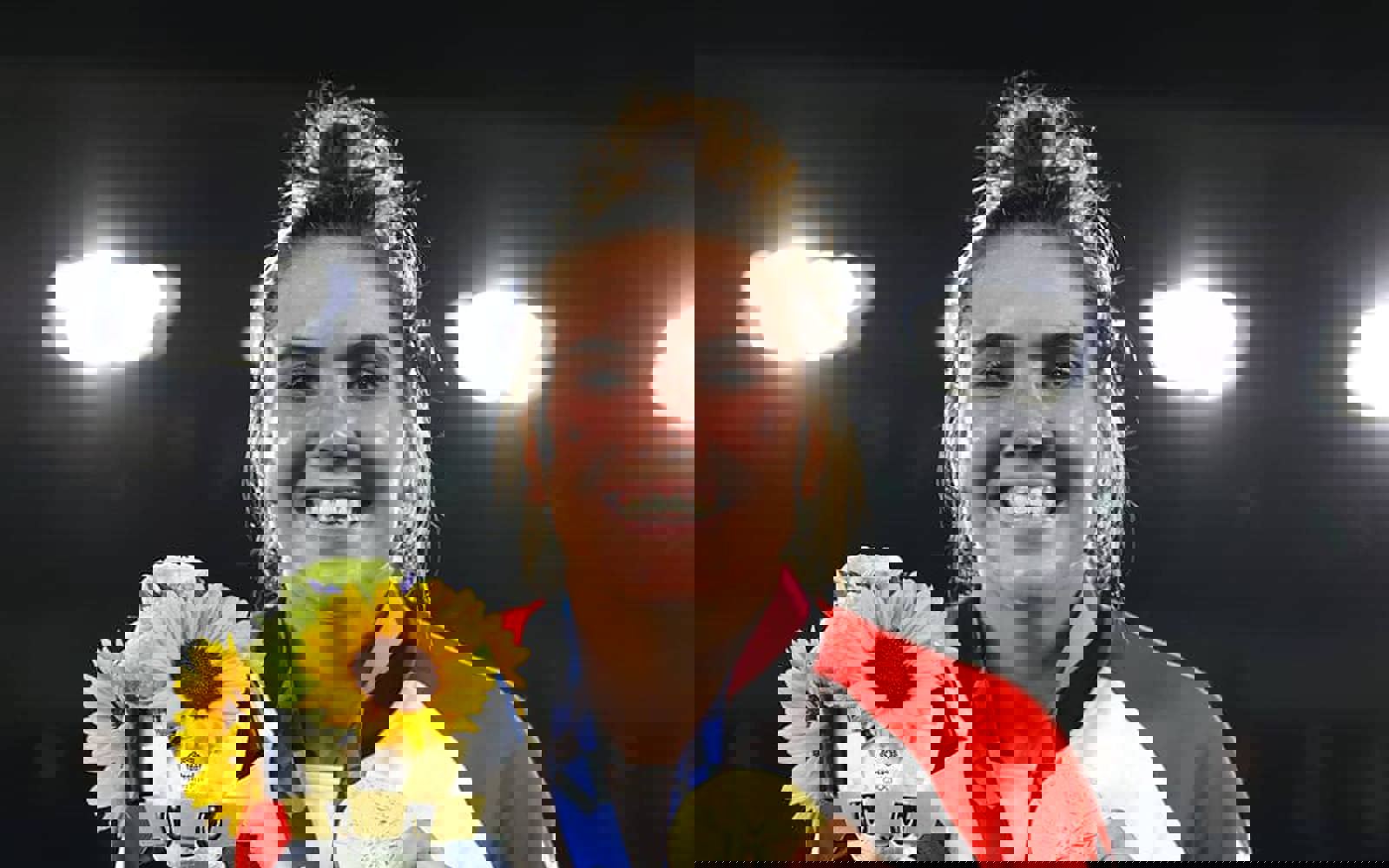 Gros plan sur le visage d'une femme aux cheveux relevés en chignon. Elle porte une veste zippée de l'équipe canadienne et tient un bouquet de tournesols. Elle porte une médaille d'or autour du cou.