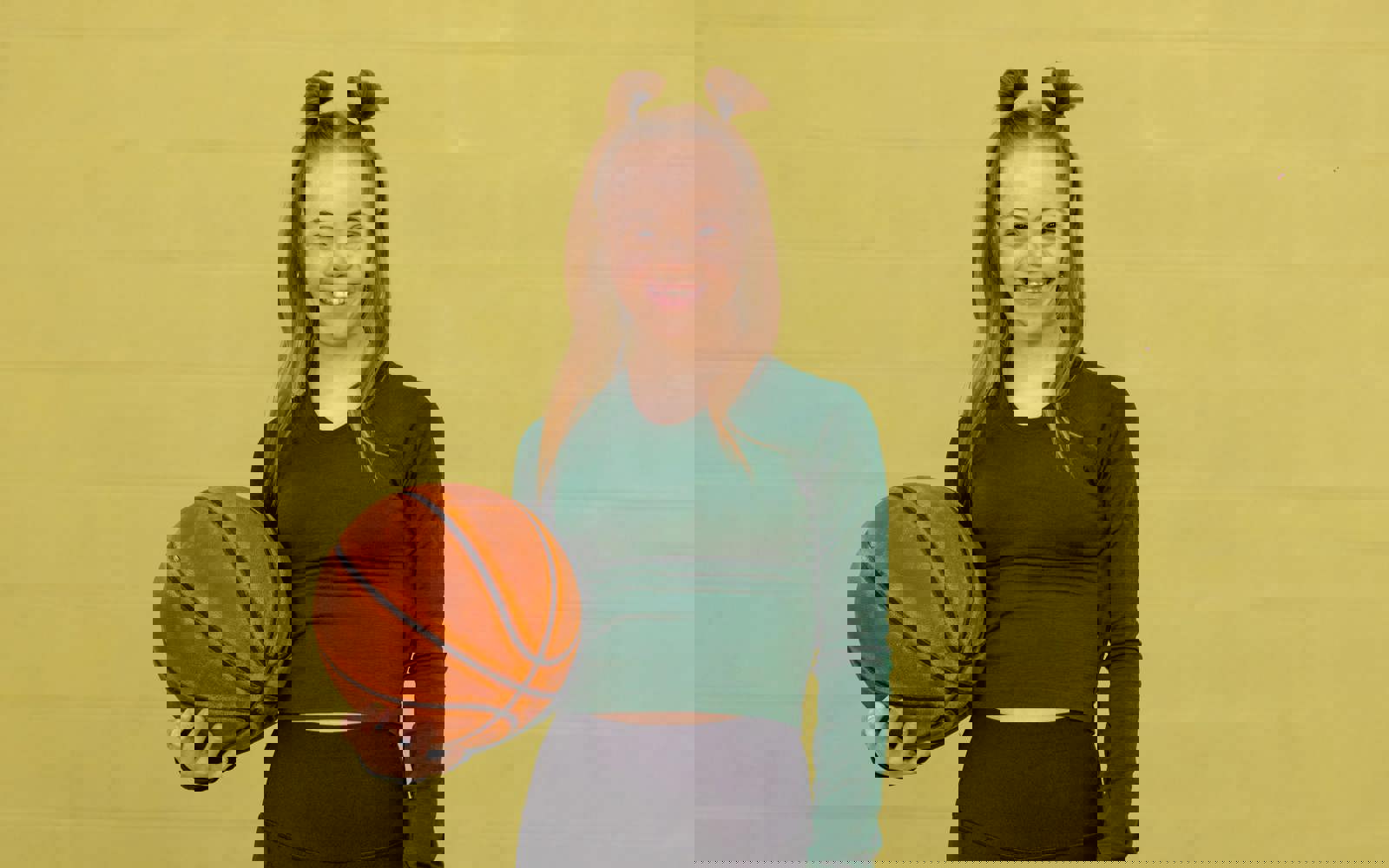 Young woman in green shirt and black pants holding a basketball