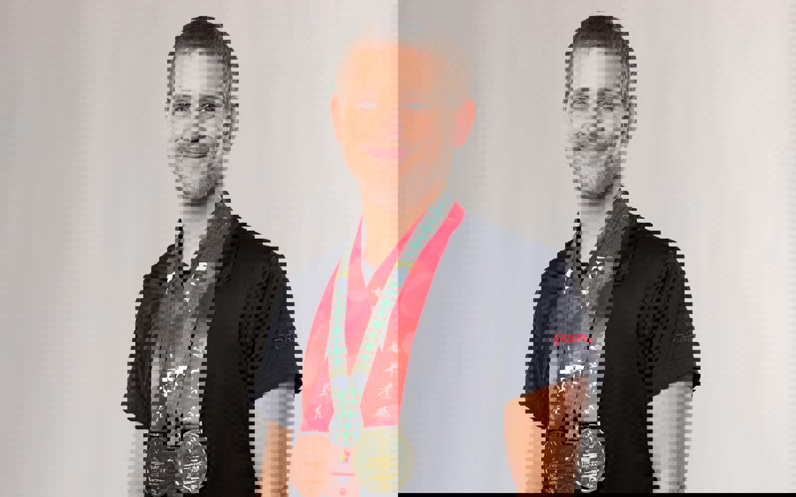 Young man in black wearing a ton of medals around his neck