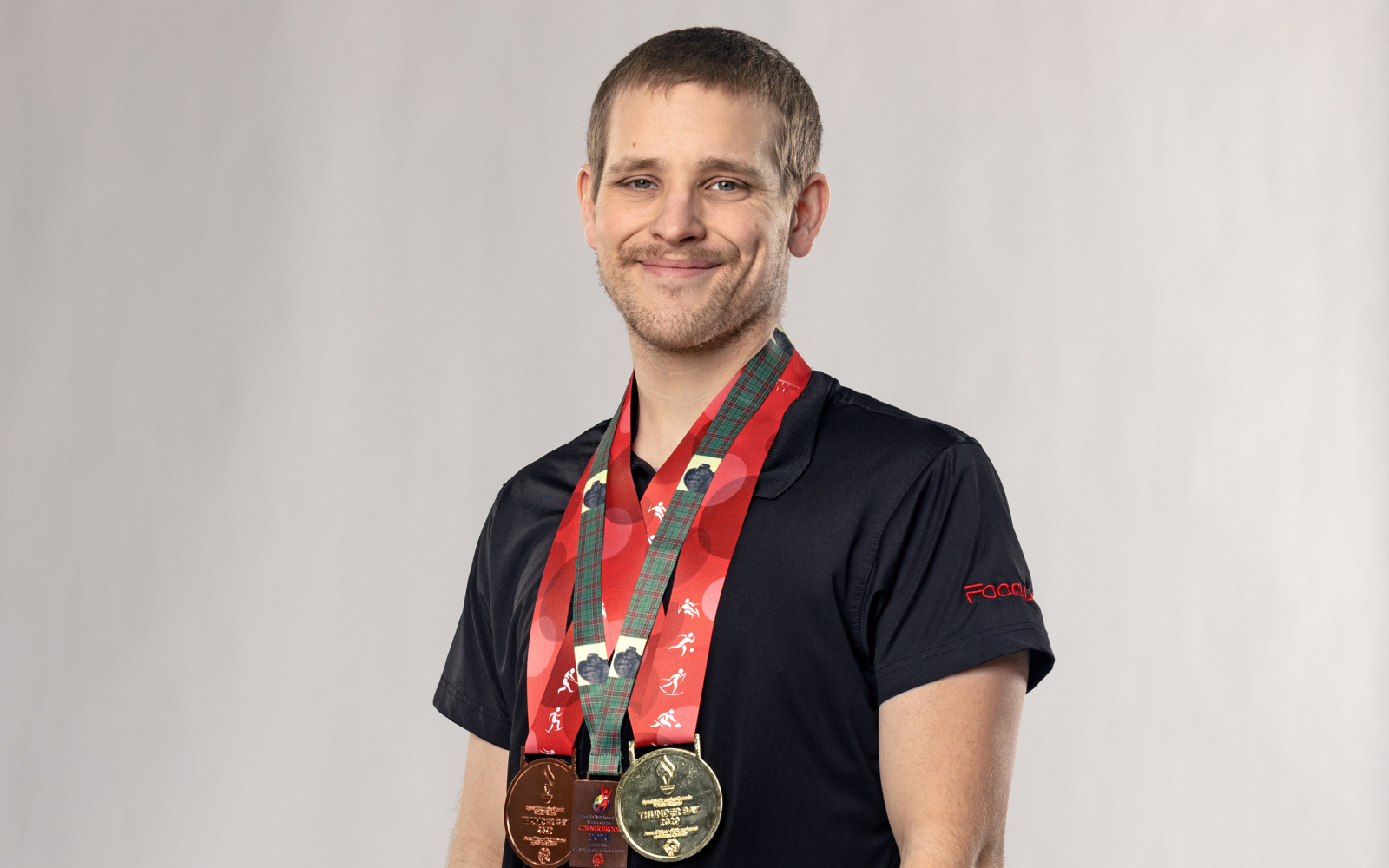 Young man in black wearing a ton of medals around his neck
