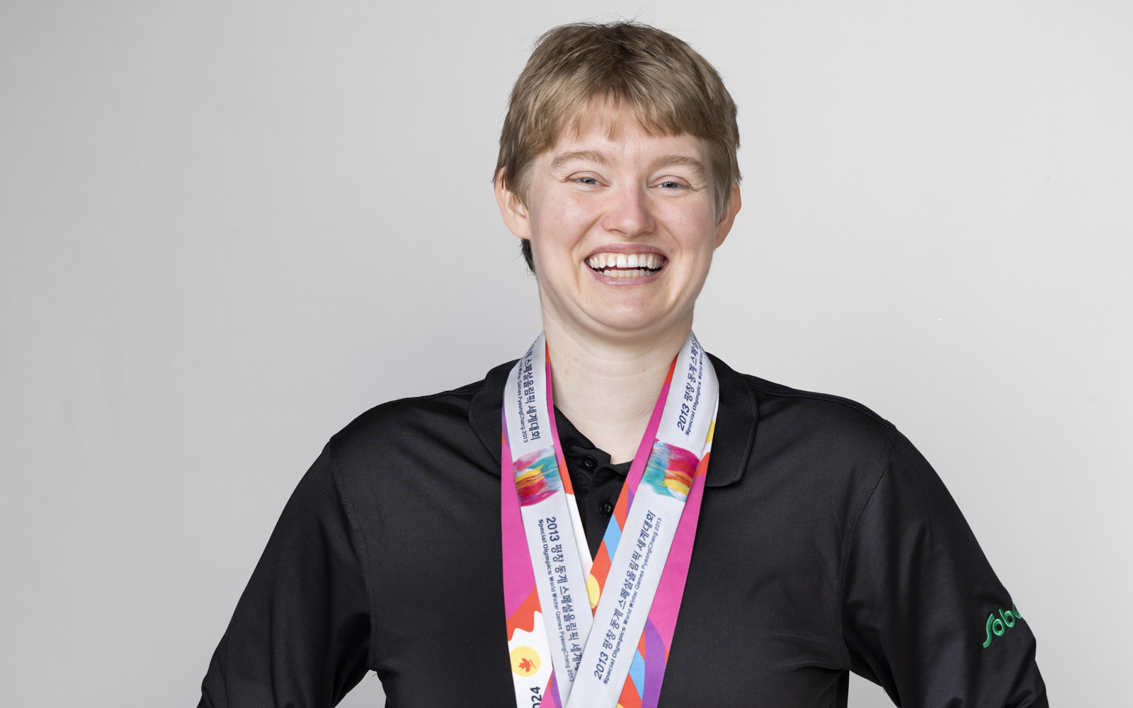 Women in a black shirt with a ton of medals around her neck 