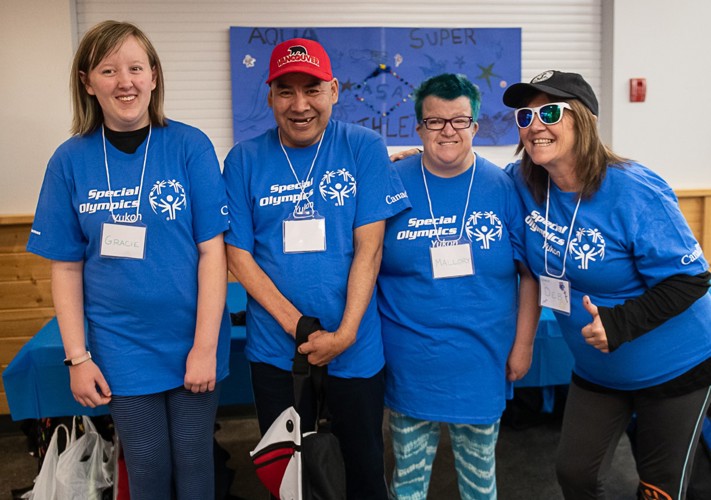 Four sport volunteers, in blue Special Olympics Yukon t-shirts, smiling at the camera.