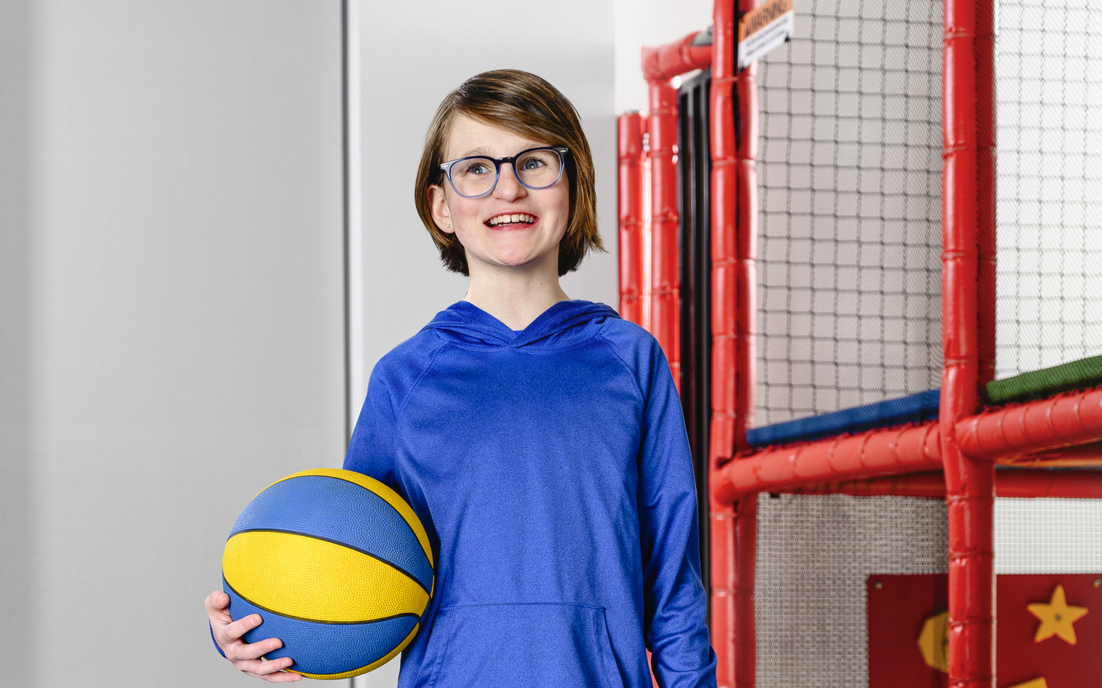 Jeune fille en chemise bleue tenant un ballon bleu et jaune