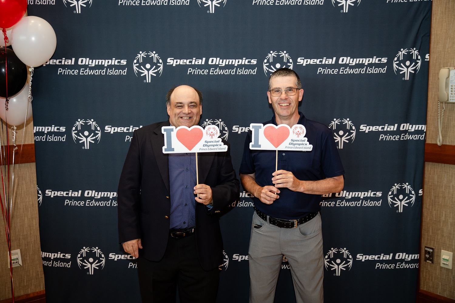 Two Special Olympics athletes standing and holding I Love Special Olympics signs