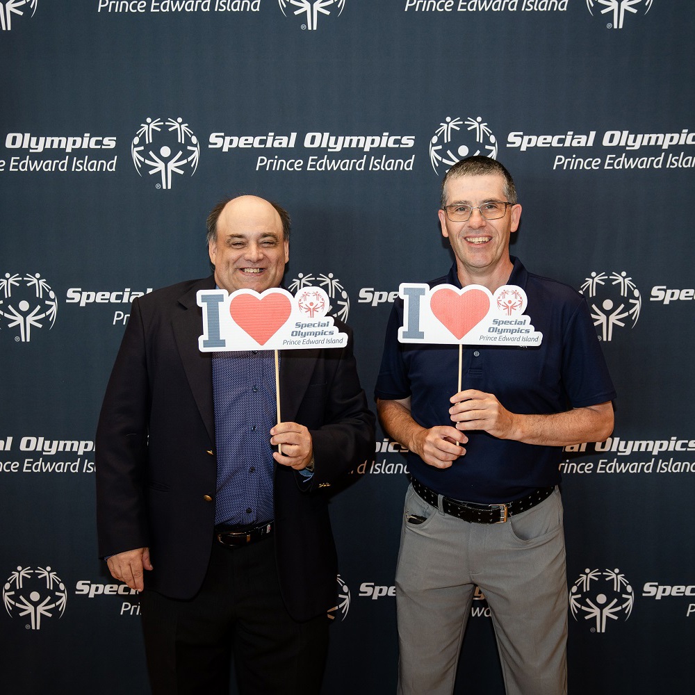Two Special Olympics athletes standing and holding I Love Special Olympics signs