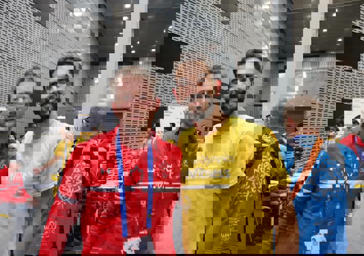 Deux hommes se tiennent côte à côte et regardent fixement la caméra. L'un porte l'uniforme de l'équipe canadienne des Jeux olympiques spéciaux, l'autre un t-shirt jaune FUNFitness.