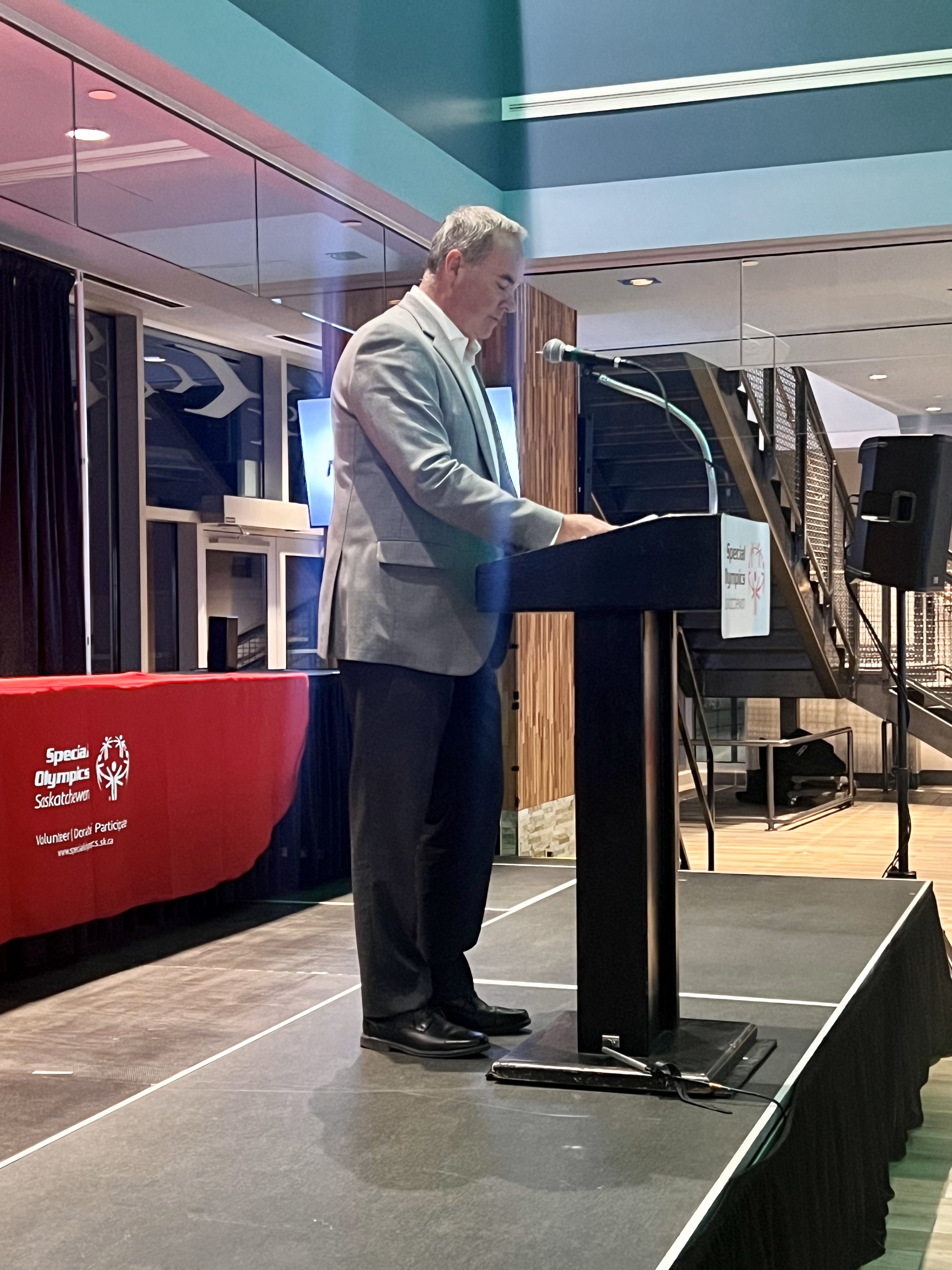 An individual is standing at a podium looking down at his speaker notes. An individual is standing at a podium looking down at his speaker notes.