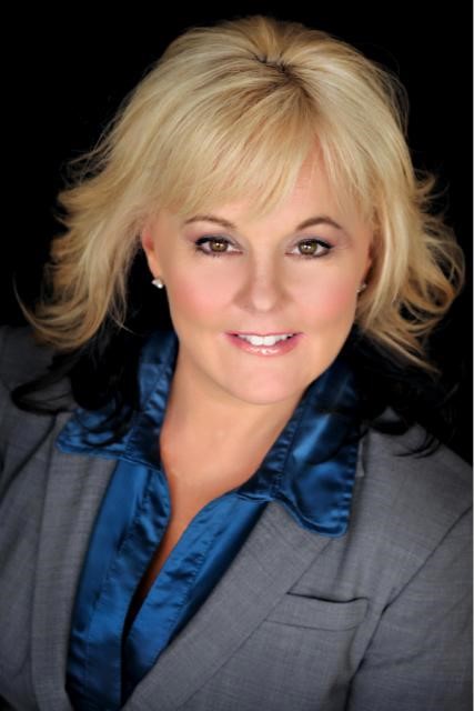 Headshot of a woman with blond hair in a grey suit jacket and blue shirt. Headshot of a woman with blond hair in a grey suit jacket and blue shirt.