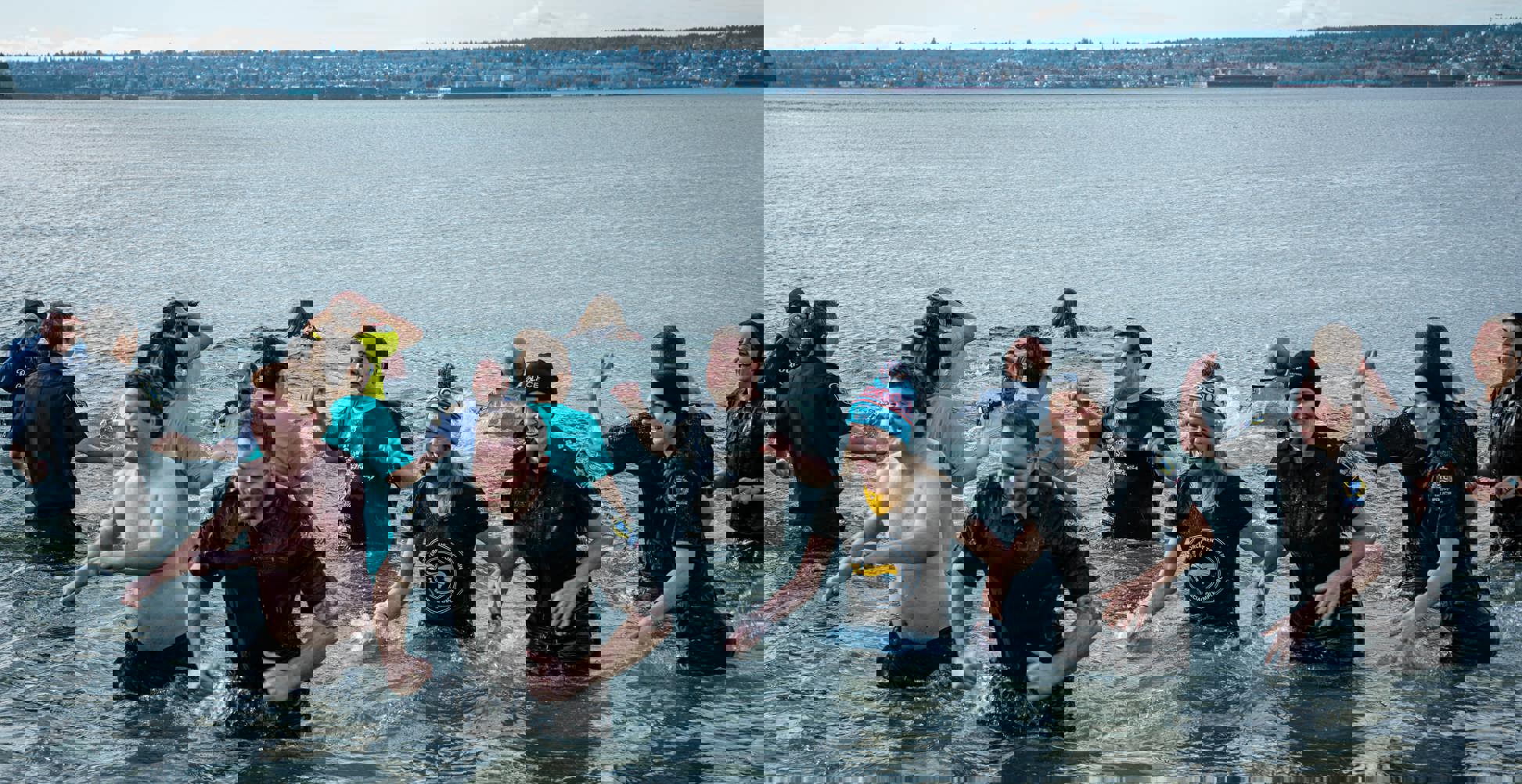 A large group of Law Enforcement Torch Run Polar Plunge participants wade out of the frigid waters with smiles on their faces.