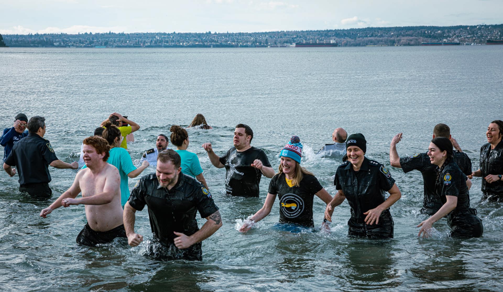 A large group of Law Enforcement Torch Run Polar Plunge participants wade out of the frigid waters with smiles on their faces.
