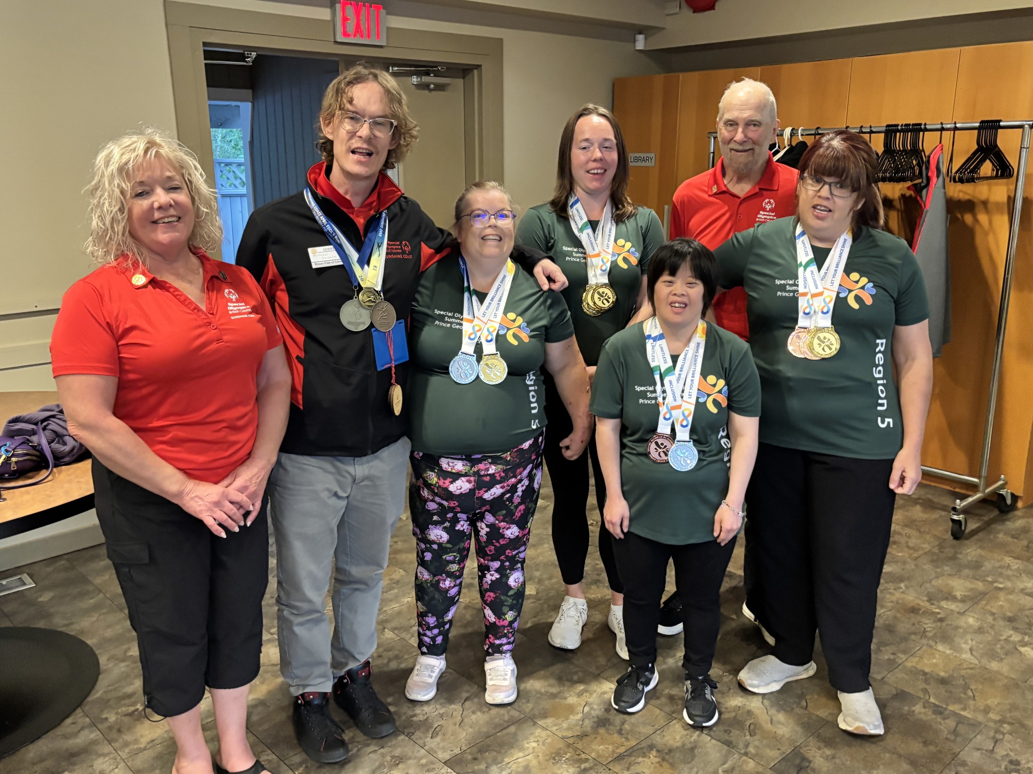 A group of volunteers and athletes standing together and smiling after a presentation.