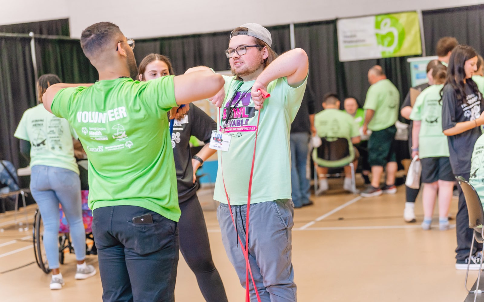 Two people standing using a tension band to workout. 