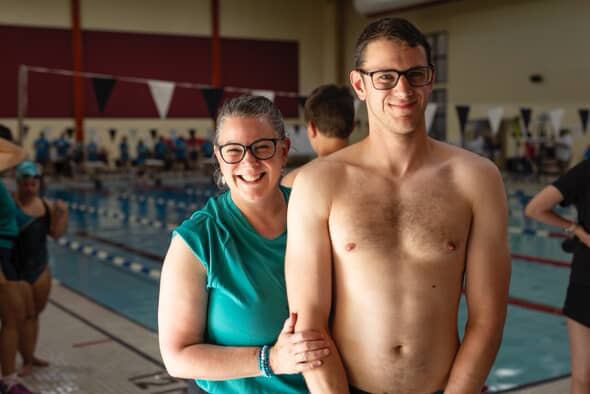 Maxim Thibault et sa mère, Jane Thibault, sourient à la caméra. Ils se tiennent devant une piscine intérieure.