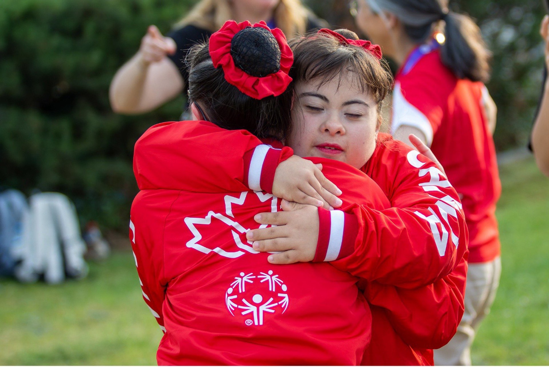 Rebecca hugging teammate wearing Special Olympics Team Canada Jackets. 