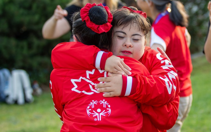 Rebecca hugging teammate wearing Special Olympics Team Canada Jackets.