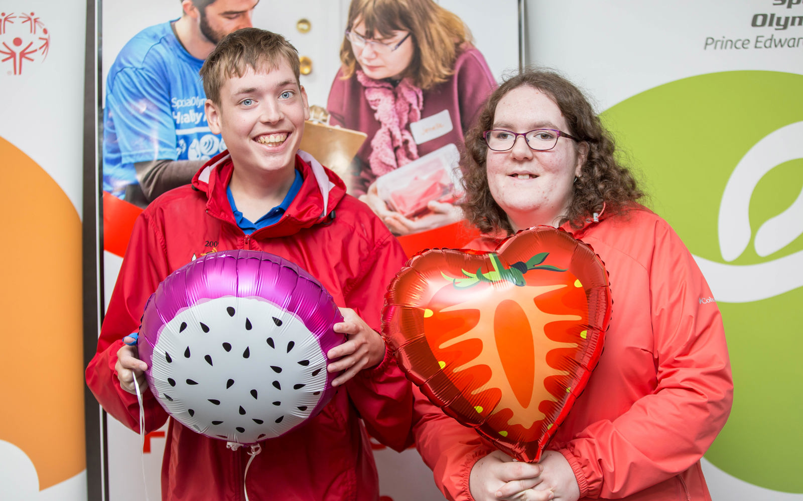 Twp people smile at the camera while holding ballons. 