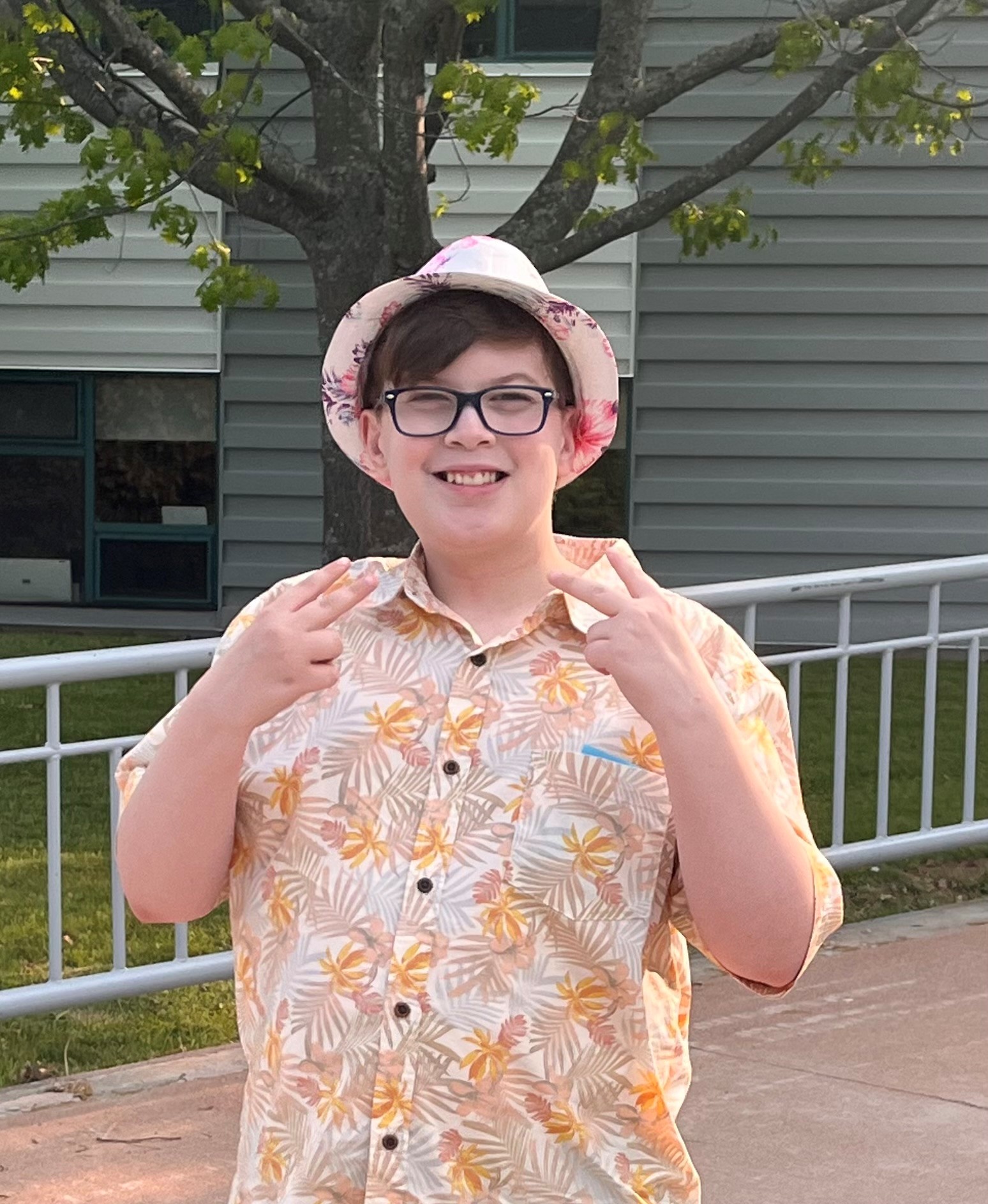 Gabe posing with his hands in peace signs outside. 
