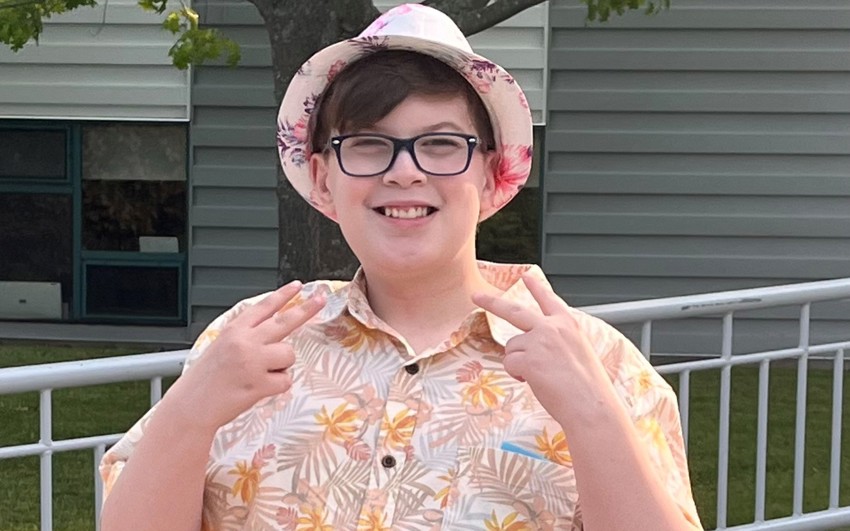 Gabe posing with his hands in peace signs outside. 