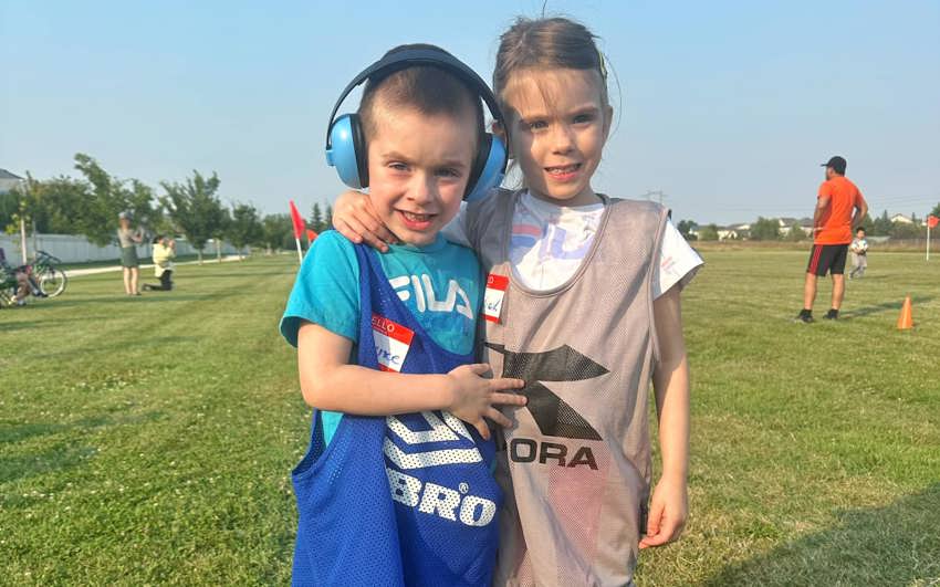 Lawrence and Maverick Von Doelln in sport pinnies standing together on a grassy field. 