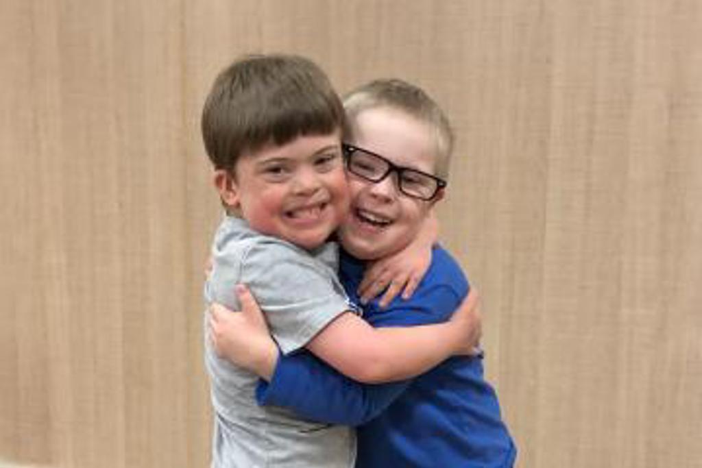 Two young athletes are hugging each other tightly and smiling for the camera.