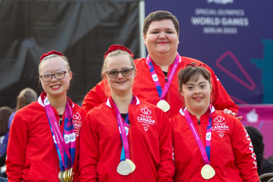 Quatre athlètes vêtus de l'uniforme de l'équipe canadienne, une médaille autour du cou.