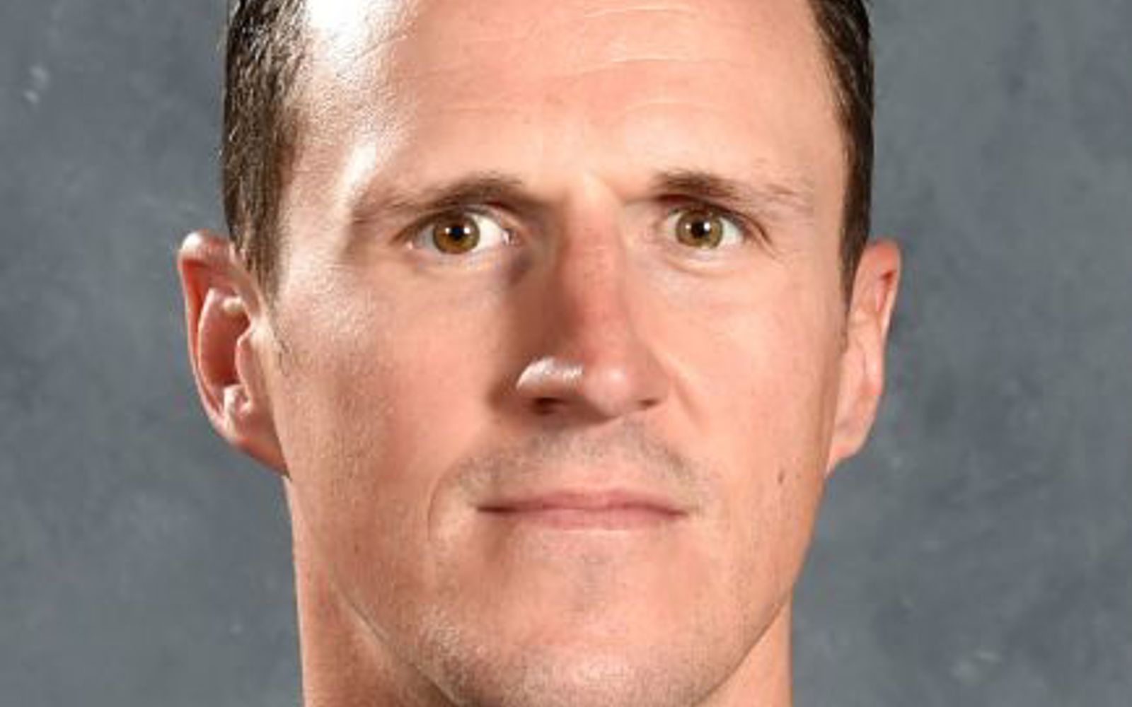 Man with dark hair wearing a hockey jersey. 