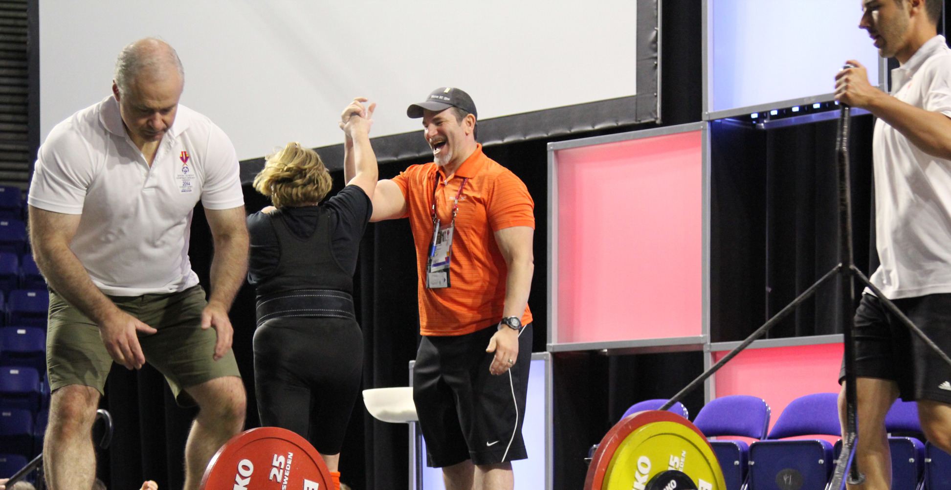 A powerlifting athlete and her coach high five each other after a good lift at a competition.