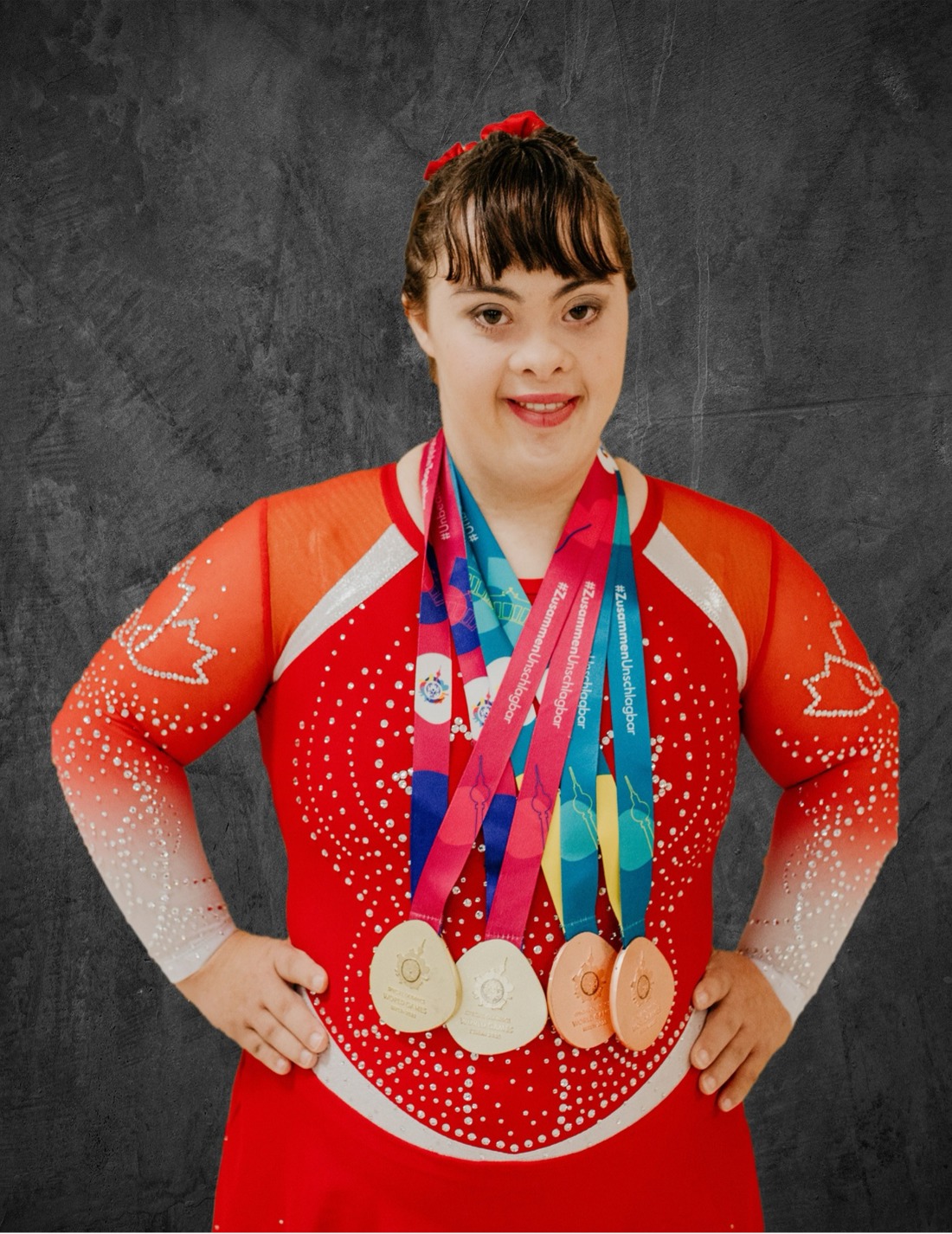 Rebecca wearing Special Olympics Team Canada 2023, Outfit posing with her hands on her hips witth 4 medals. 