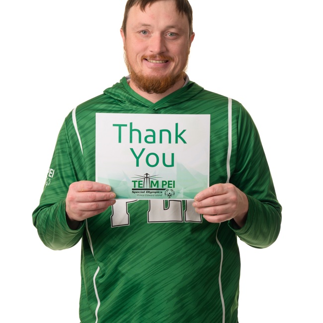 Team PEI 2026 Athletics athlete, Jeremy Wall, standing with a thank you sign