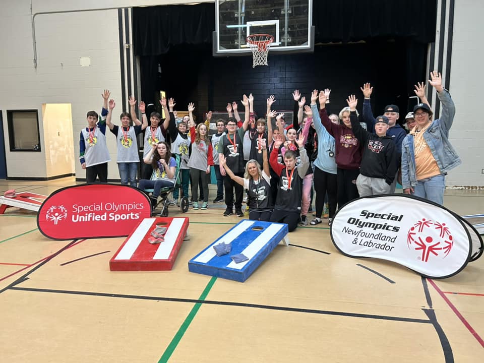 Diverse group of people in a gym. In front of them is two cornhole games. Diverse group of people in a gym. In front of them is two cornhole games.
