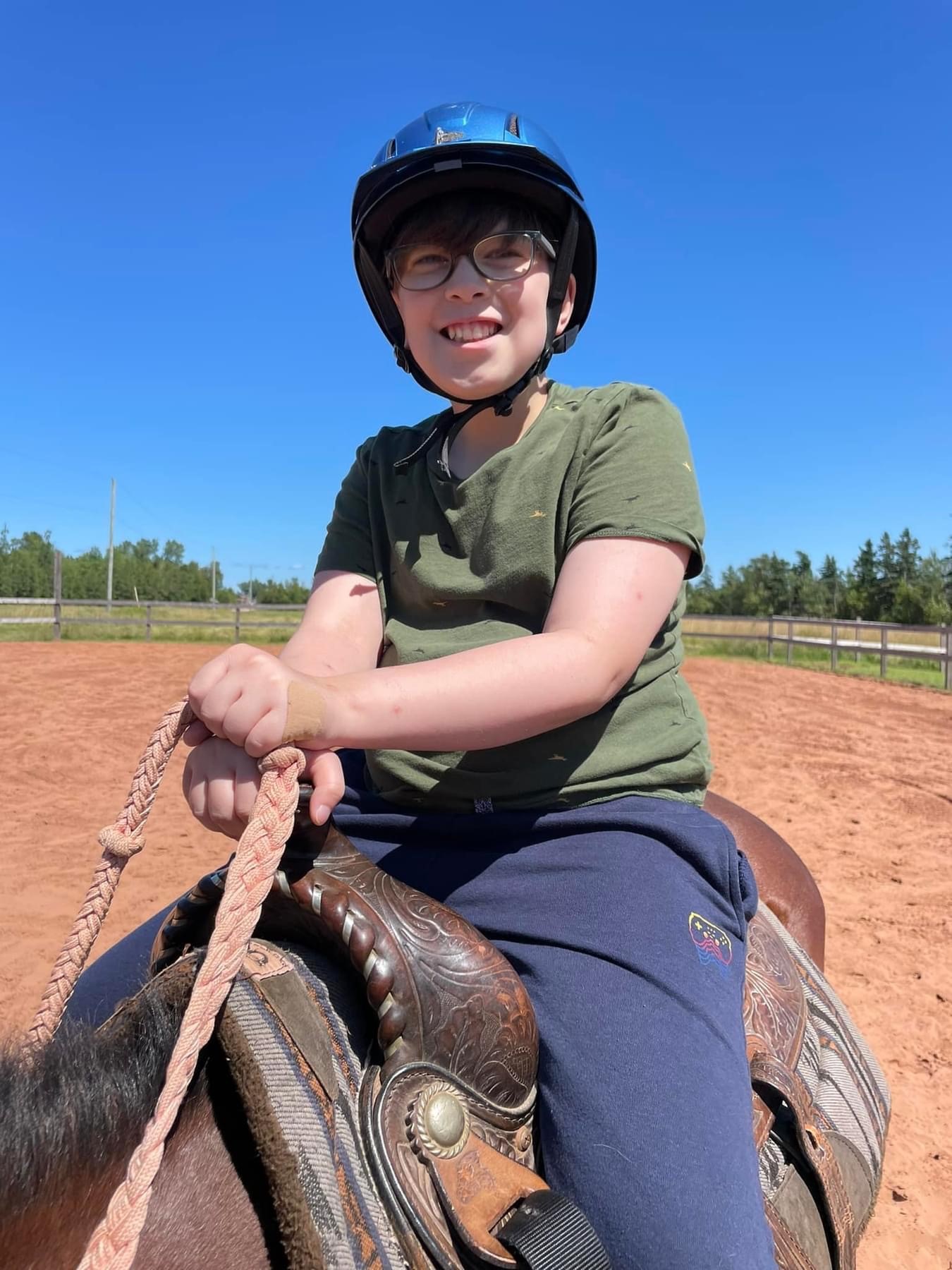 Gabe wearing a helmet while sitting on top of a horse outside. 