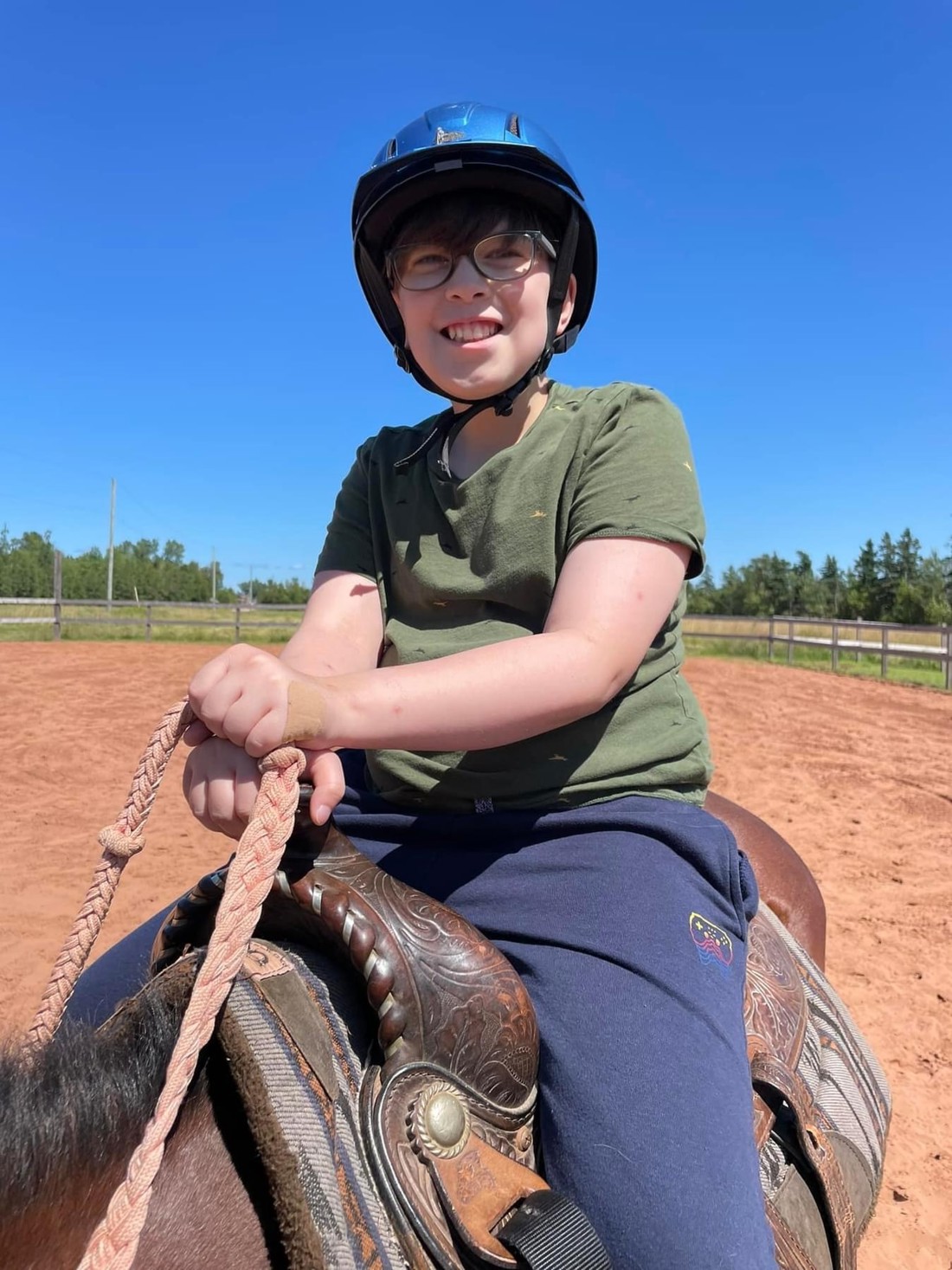Gabe wearing a helmet while sitting on top of a horse outside. 