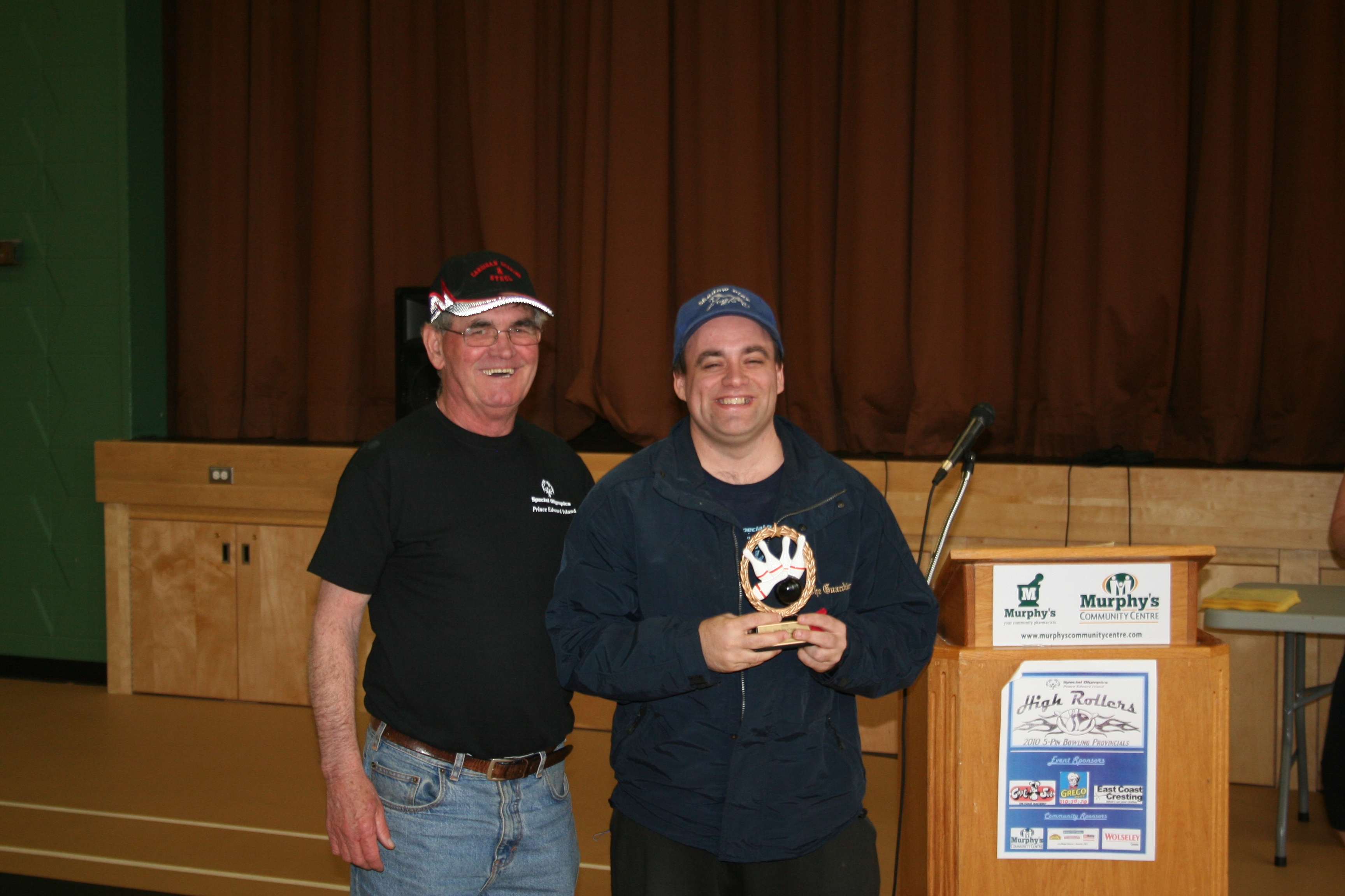 A Special Olympics bowling coach with an athlete holding a trophy; Rickey Burns