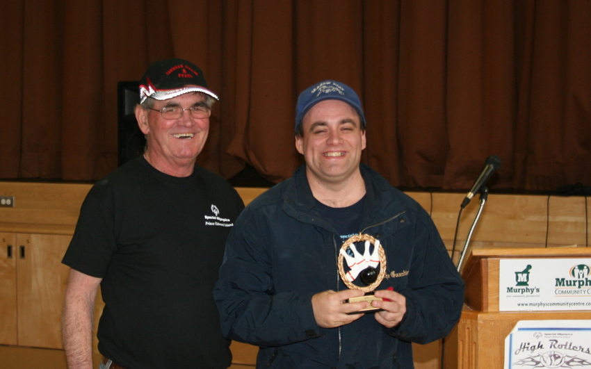 A Special Olympics bowling coach with an athlete holding a trophy; Rickey Burns