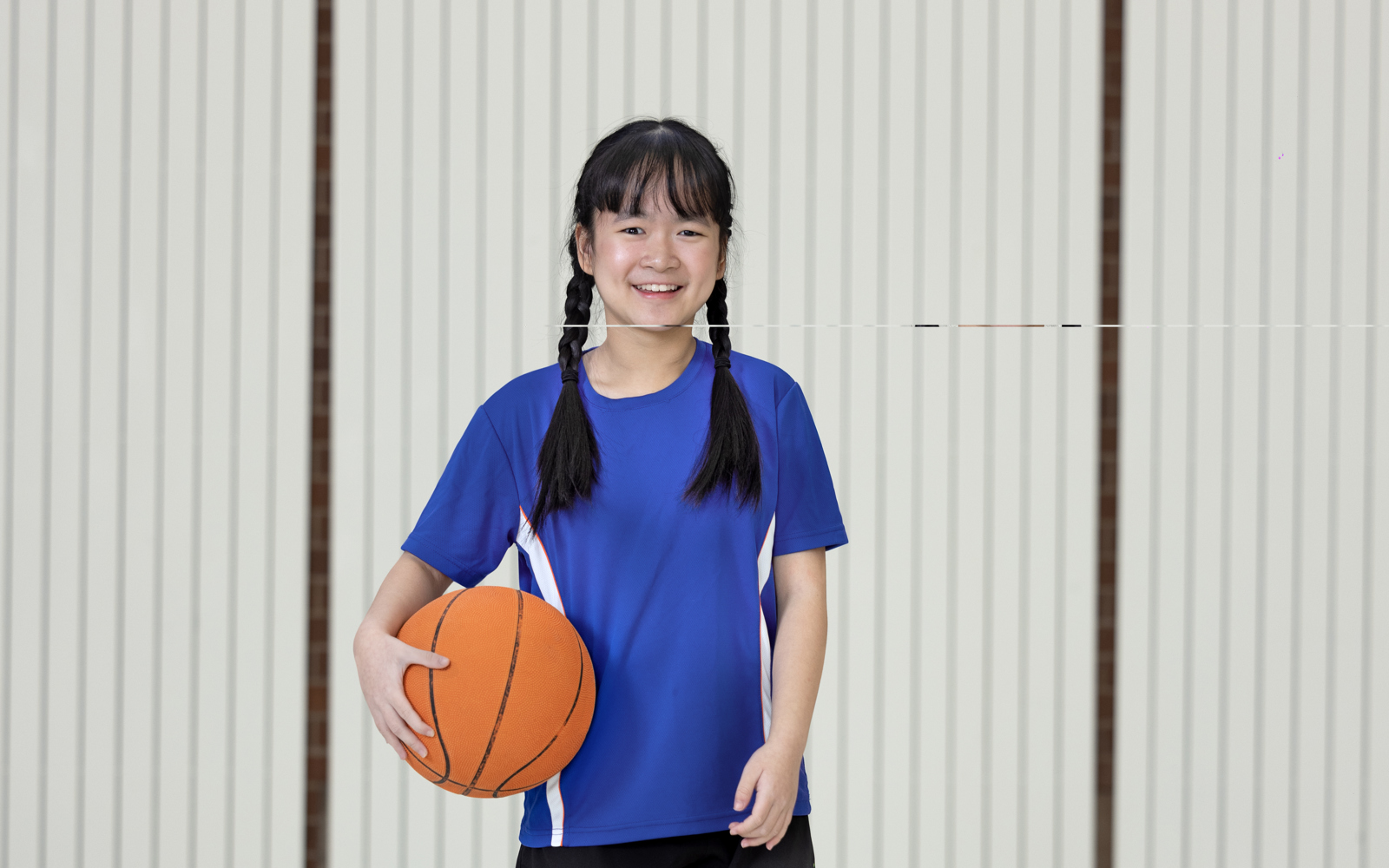 Jeune fille en chemise bleue tenant un ballon de basket