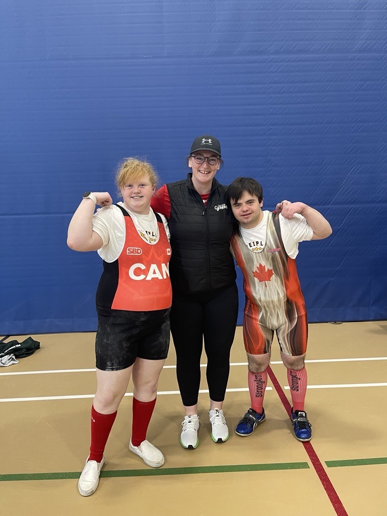 2 Special Olympics Powerlifting athletes with their Coach at a competition