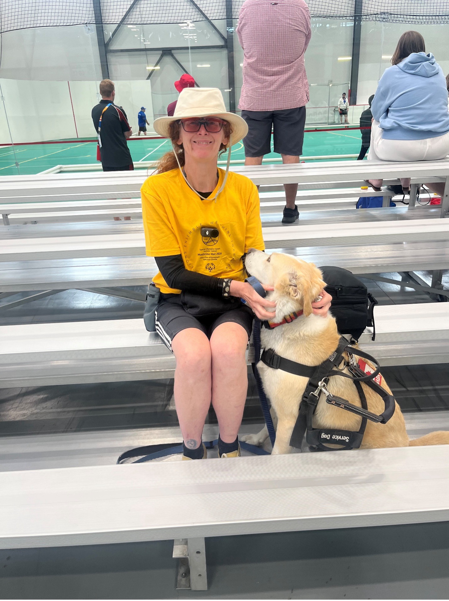 Kelly Boreson with her service dog sitting on bleachers at the Special Olympics Canada Summer Games Medicine Hat 2026.