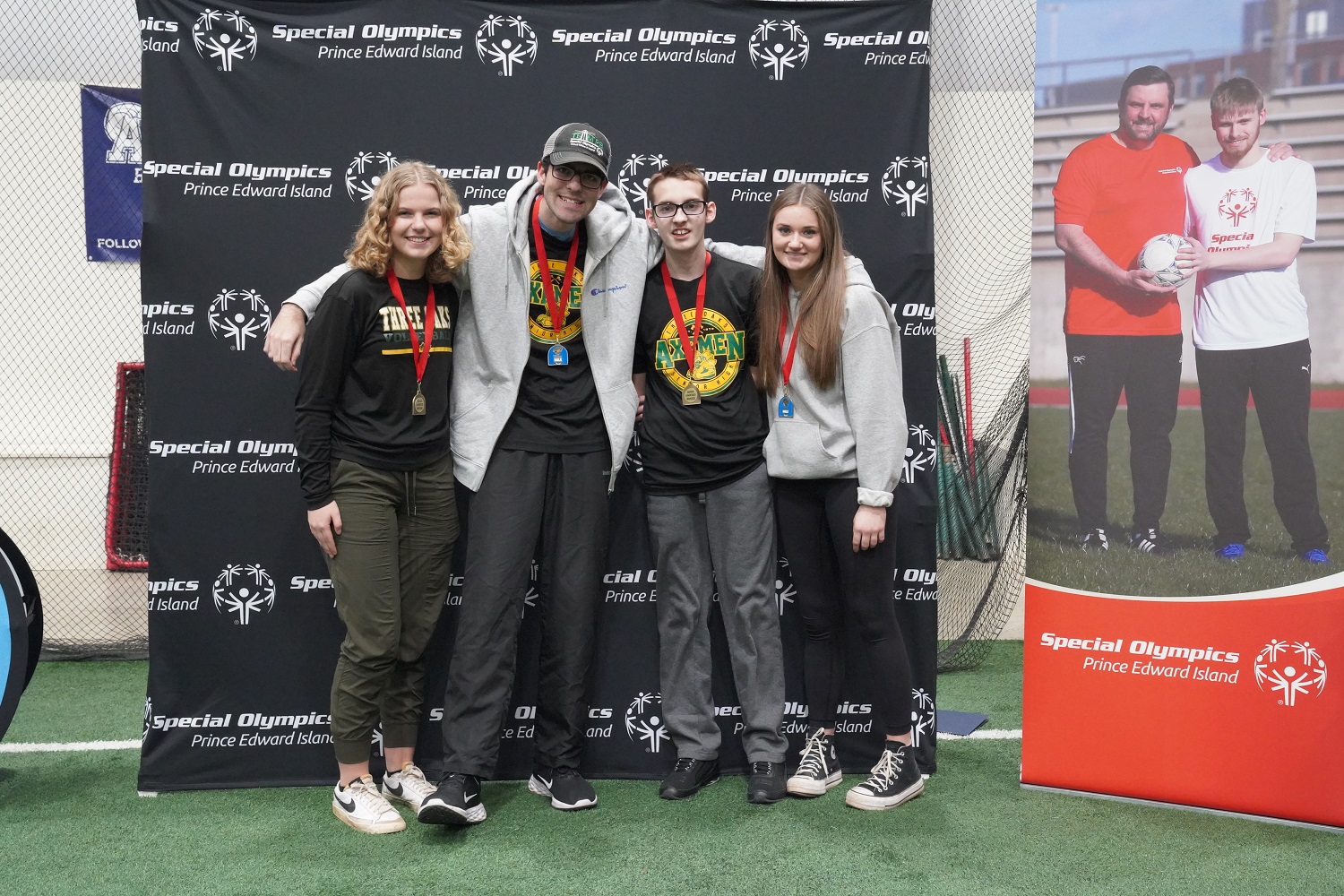 A four person Unified Bocce team, with their gold medals, stands in front of a backdrop 